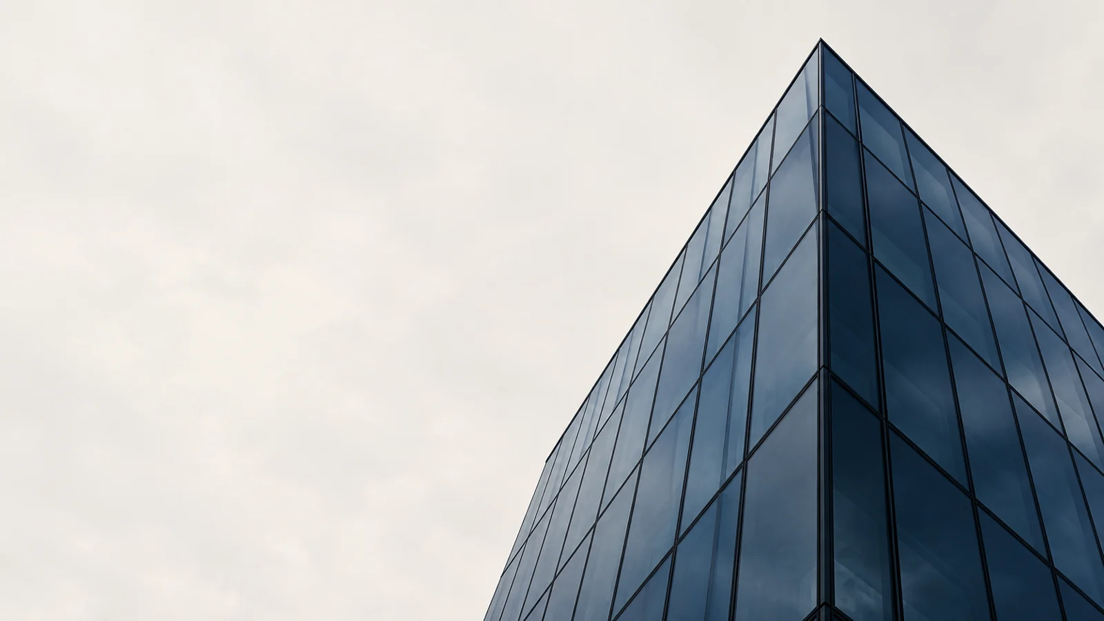Vertice di un edificio in vetro blu contro un cielo chiaro